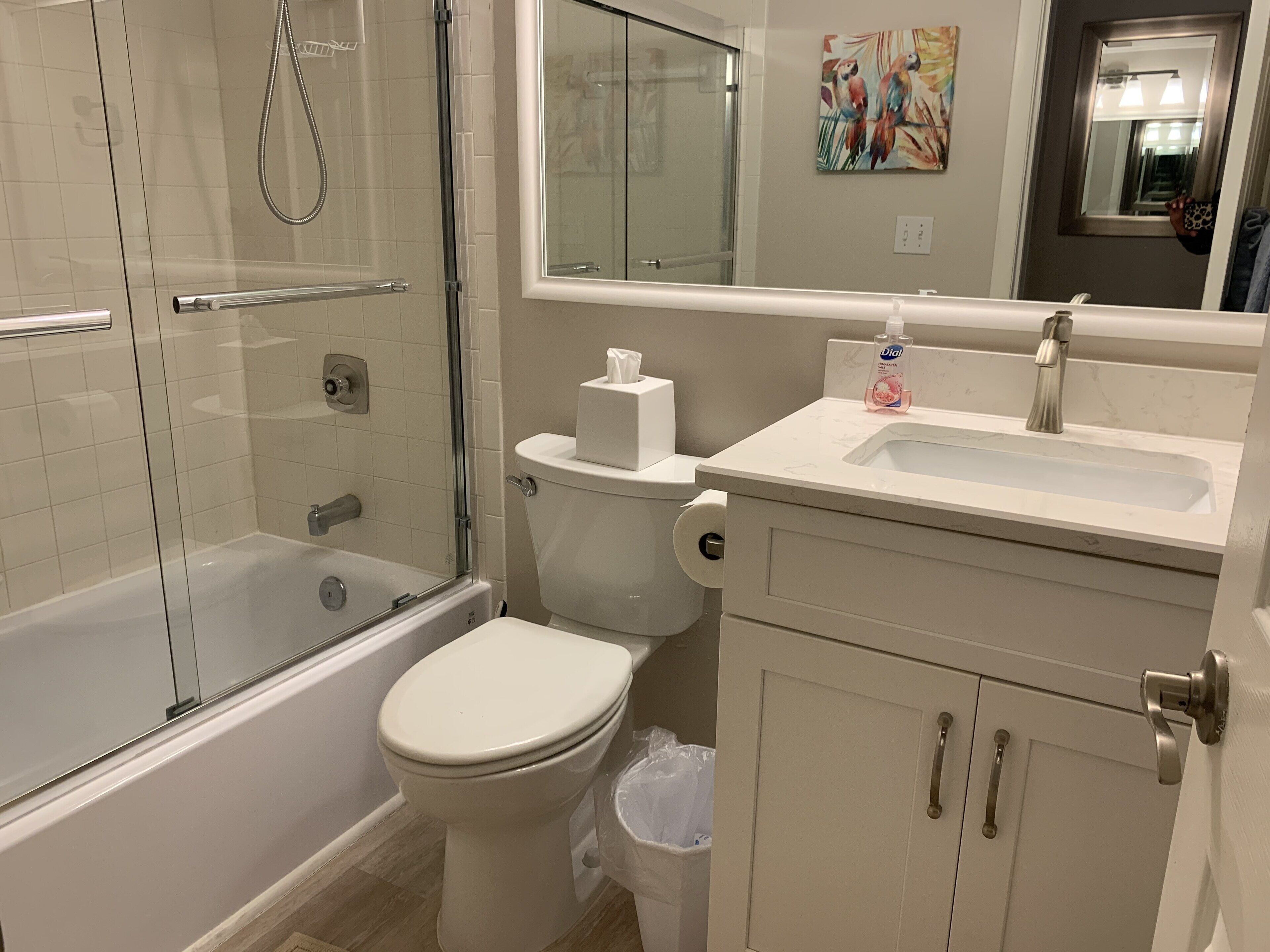 A bathroom with a glass-enclosed shower, a toilet, a sink, and a cabinet.