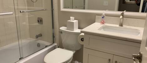 A bathroom with a glass-enclosed shower, a toilet, a sink, and a cabinet.
