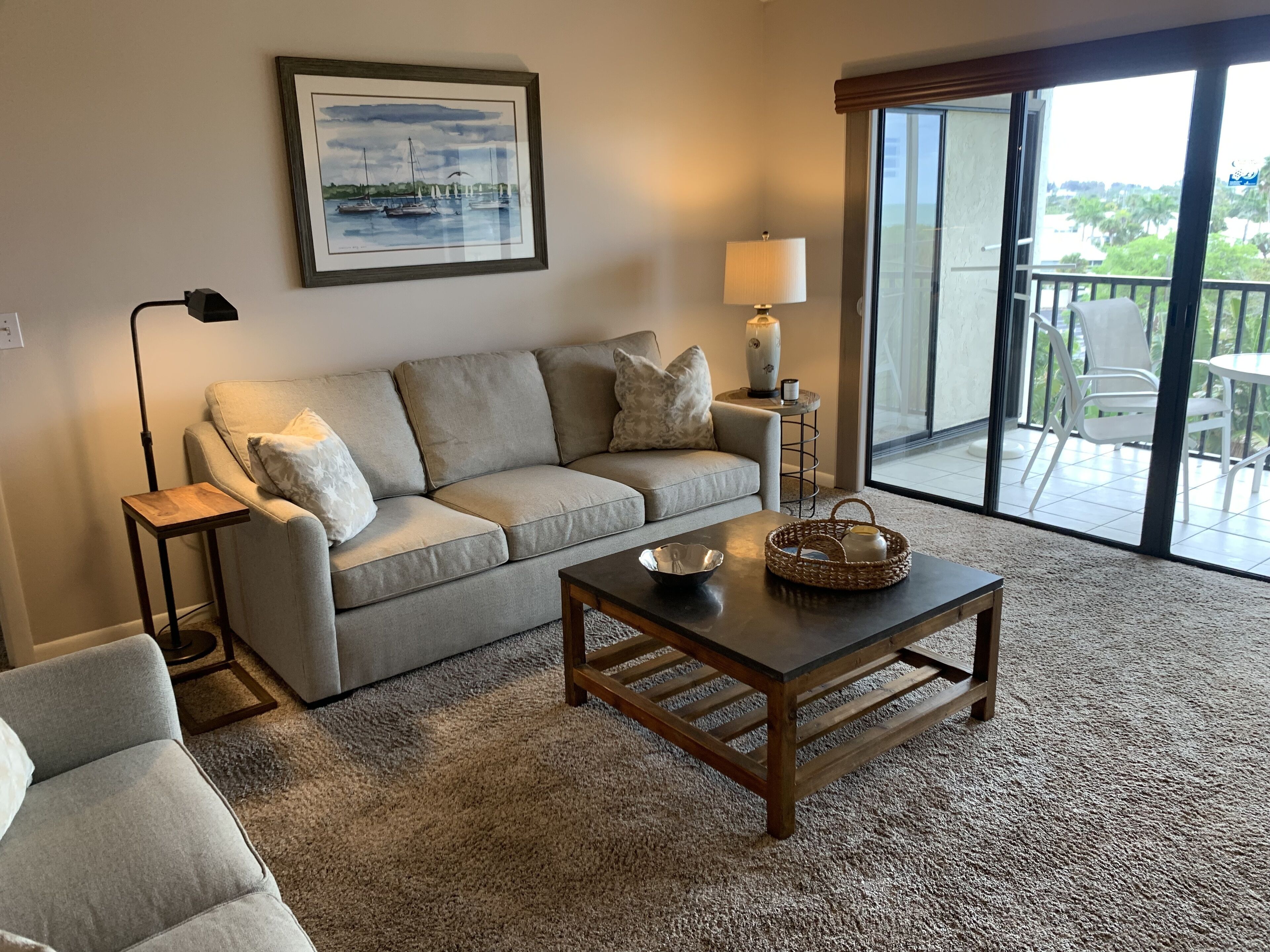 A living room with a sofa, a coffee table, a lamp, and a framed painting on the wall.