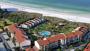 A resort with multiple buildings, a central pool, and a beach.