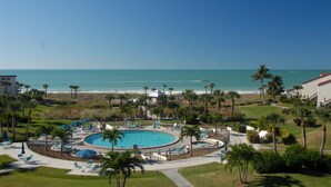A resort with a circular pool, lounge chairs, and palm trees.