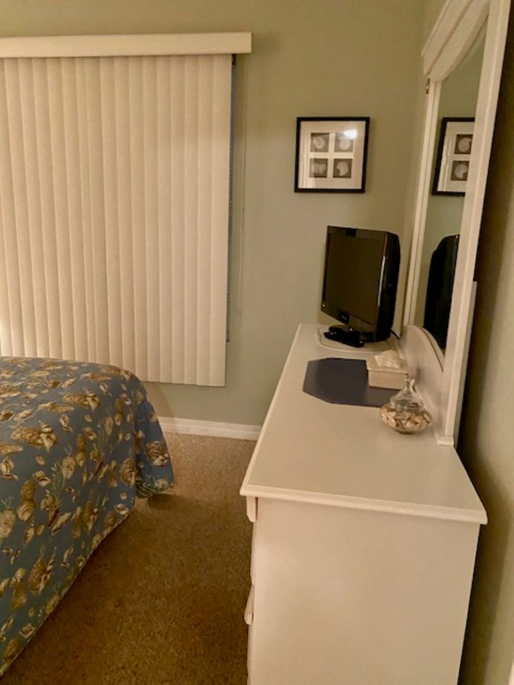 Een slaapkamer met een bed, een kapstok, een televisie en een spiegel.