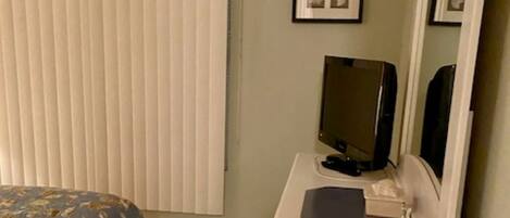 A bedroom with a bed, a dresser, a television, and a mirror.