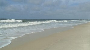 A beach with waves approaching the shore, a clear sky, and no visible structures or people. - Low Rates ! Gulf View; Palms, Grnd Flr; Weekly discounts (Gulf Shores)