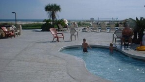 A pool area with lounge chairs and a palm tree. - Low Rates ! Gulf View; Palms, Grnd Flr; Weekly discounts (Gulf Shores)