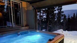 Un bain à remous avec vue sur un paysage enneigé et des arbres.