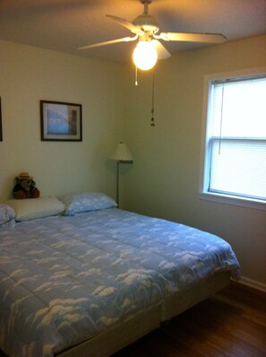 A bedroom with a bed, a ceiling fan, a window with blinds, a lamp, and a framed picture on the wall. - Pet friendly sound side 3 Bdrm/2Bth Non Smoking Beach Box Private Home (Kill Devil Hills)