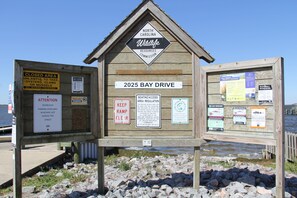 A wooden information board with multiple signs, including one for the 2025 Bay Drive, another for North Carolina Wildlife Resources Commission, and several others related to boating access and regulations. - Pet friendly sound side 3 Bdrm/2Bth Non Smoking Beach Box Private Home (Kill Devil Hills)
