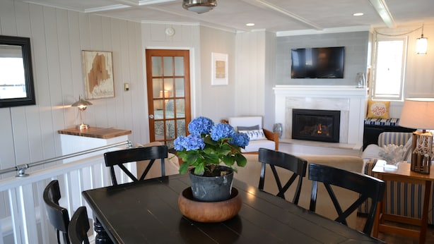 Un comedor con mesa de madera, sillas y una planta en maceta con flores azules.