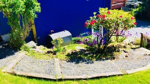 Une maison bleue avec un jardin, une terrasse en bois et un bateau amarré à l’extérieur.