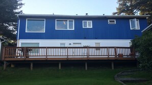 Une maison à deux étages avec une façade bleue et une terrasse en bois.