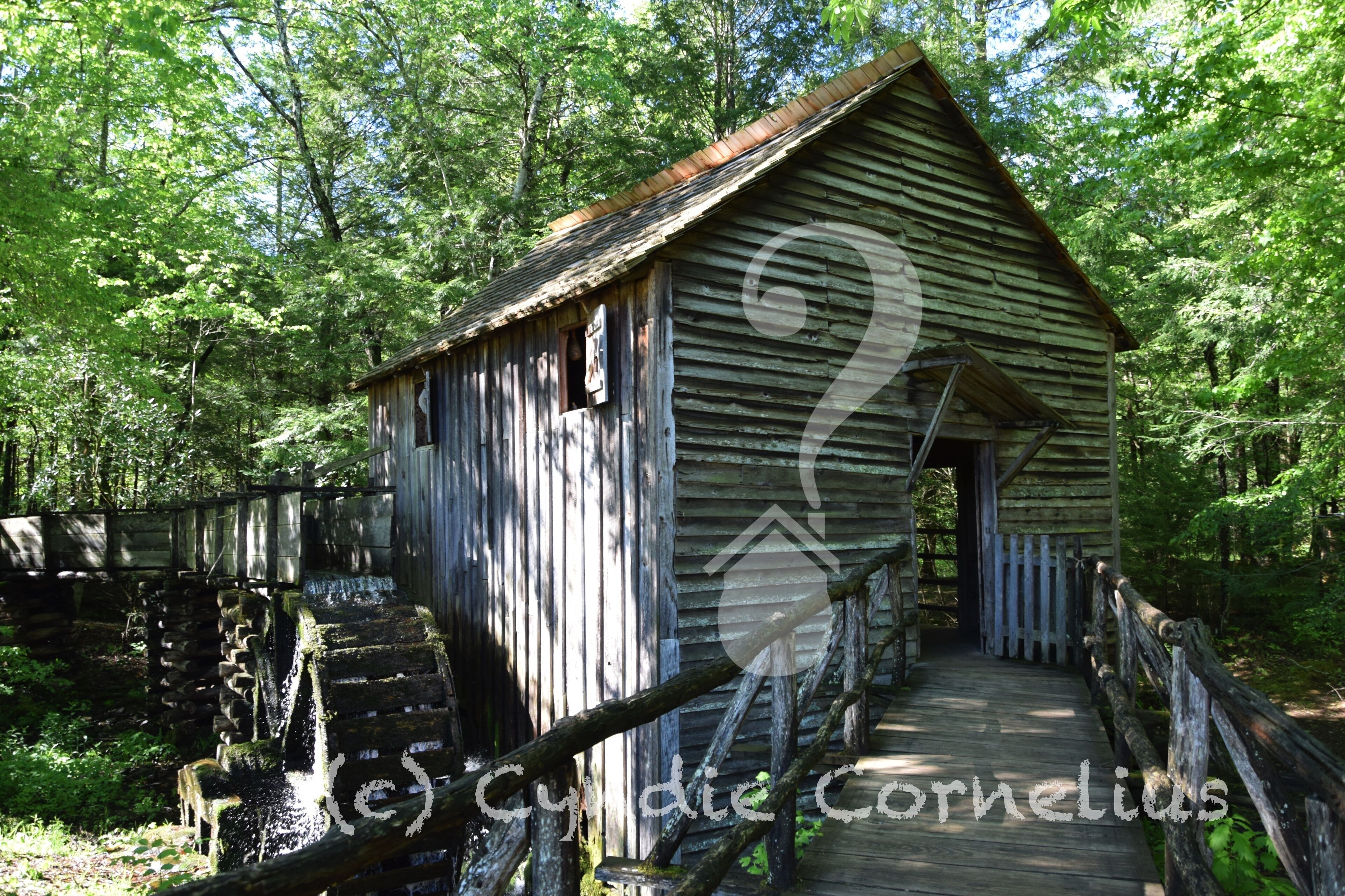 A rustic wooden structure with a porch and a wooden staircase leading up to it.