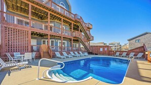 A pool area with lounge chairs and a staircase leading to a building with multiple balconies. - Oceanfront Dog Friendly Rodanthe Home w/ Pool, Hot Tub, Game Room, Home Theater (Rodanthe)