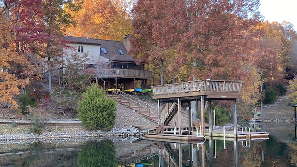 Una cabaña junto al lago con un muelle y una terraza de madera.