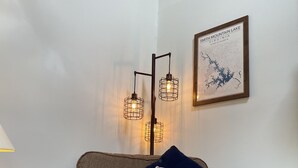Un salón acogedor con un sillón marrón, una lámpara, un mapa enmarcado y un cartel que dice "LAKE HOUSE".