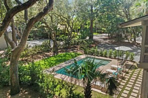 A pool area with a rectangular pool, surrounded by a paved deck, and adjacent to a building with a covered seating area. - Beachwalk Cottage – Steps to Beach, Free Seasonal Pool Heat, Sleeps 10, 4 King Suites (Hilton Head Island)