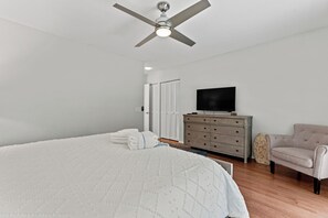 Un dormitorio con cama, cómoda, televisor y silla.