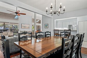 A dining area with a wooden table and chairs, a ceiling fan, and a chandelier. - Beachwalk Cottage – Steps to Beach, Free Seasonal Pool Heat, Sleeps 10, 4 King Suites (Hilton Head Island)