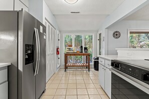 Eine moderne Küche mit einem Edelstahlkühlschrank, einem Holztisch und einer Kaffeemaschine.
