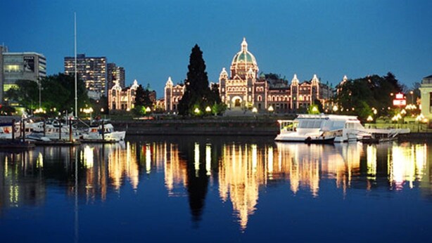 A waterfront cityscape with a prominent domed building reflecting on calm water. - WATER'S EDGE DOWNTOWN SUNSET WEST BALC, KING BDRM, A/C, 90 DAY MIN, (Victoria)