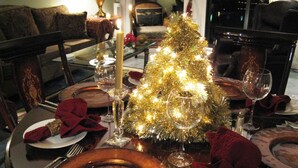 A dining table set for a meal with a small golden Christmas tree centerpiece, candles, and formal tableware. - WATER'S EDGE DOWNTOWN SUNSET WEST BALC, KING BDRM, A/C, 90 DAY MIN, (Victoria)