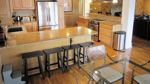 Una cocina con encimeras de granito, electrodomésticos de acero inoxidable y una isla central con taburetes de bar.