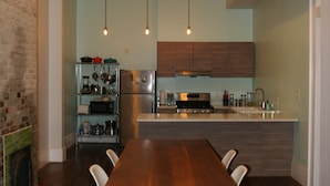 A modern kitchen with wooden cabinets, a central island, and a dining area with a wooden table and chairs. - Elegant home steps from St. Charles Ave, parades, and downtown attractions. (New Orleans)