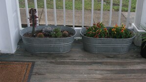 Two metal planters on a wooden deck with a white fence in the background. - Elegant home steps from St. Charles Ave, parades, and downtown attractions. (New Orleans)