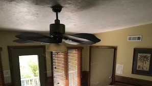Une chambre dotée d’un jacuzzi, d’un ventilateur de plafond, d’une porte offrant une belle vue et d’un tableau encadré au mur.