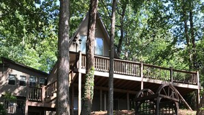 Une cabane rustique avec des fondations en pierre, une terrasse en bois et un arc en pierre.