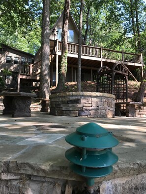 Surrounded by mature trees, this lodge features a wooden deck and a stone staircase leading to a second level.