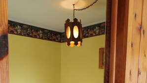 Een slaapkamer met een bed, een houten deur en een hanglamp.