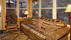 A cozy room with a patterned sofa, a wooden armchair, and a rug. - Private, Secluded, Quiet with Large Creek sitting on over 6 acres of wooded land (Gatlinburg)
