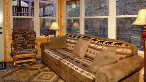 Ein gemütliches Zimmer mit einer gemusterten Couch, einem Holzschaukelstuhl und einem Teppich.