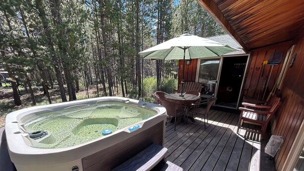 A hot tub on a wooden deck with a table and chairs, surrounded by trees. - Mt Bachelor, Deschutes River Cozy Cabin w/HotTub, Minutes to Sunriver (Bend)