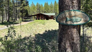 A cabin with a wooden exterior and a green roof, surrounded by a forested area. - Mt Bachelor, Deschutes River Cozy Cabin w/HotTub, Minutes to Sunriver (Bend)