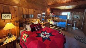 A cozy cabin-style bedroom with a large bed, a desk, and a bunk bed. - Mt Bachelor, Deschutes River Cozy Cabin w/HotTub, Minutes to Sunriver (Bend)