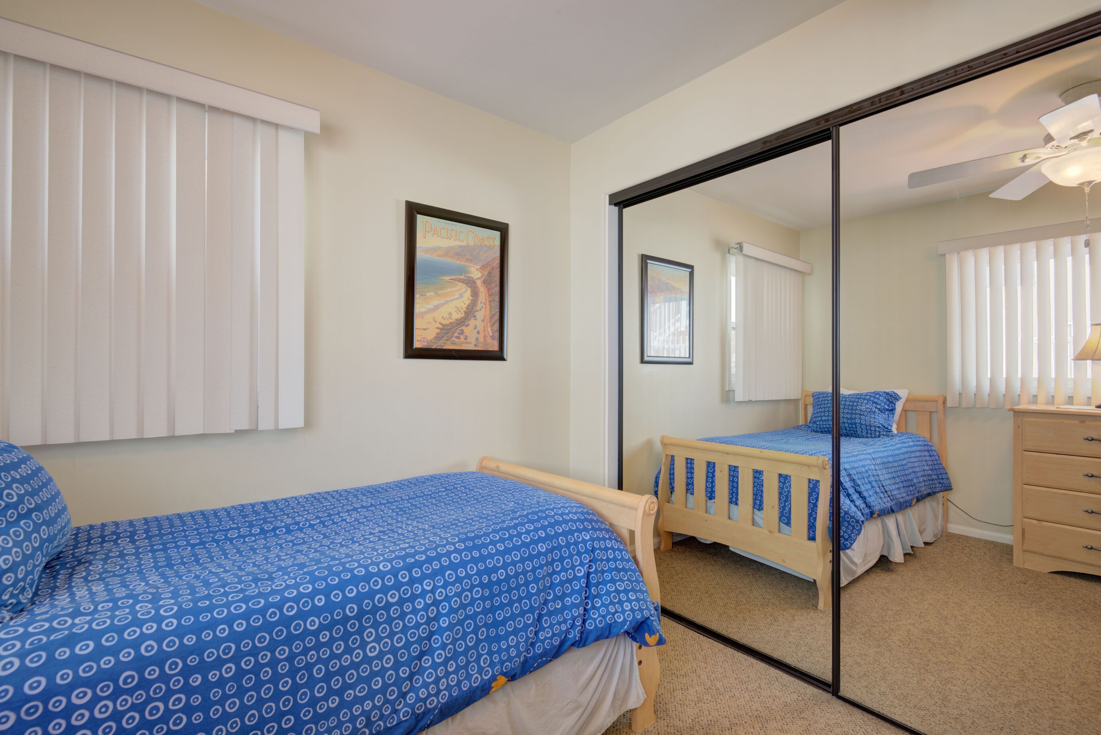 Une chambre avec deux lits, un grand miroir et un ventilateur de plafond.