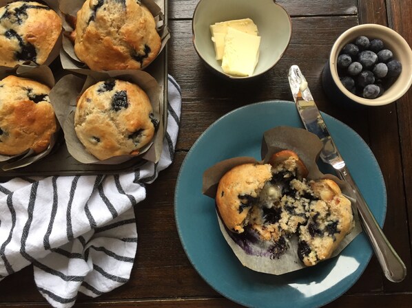 Muffins on a tray, a plate with a muffin, a bowl of butter, and a bowl of blueberries. - Ocean view, Galiano Island retreat plus more (Galiano Island)