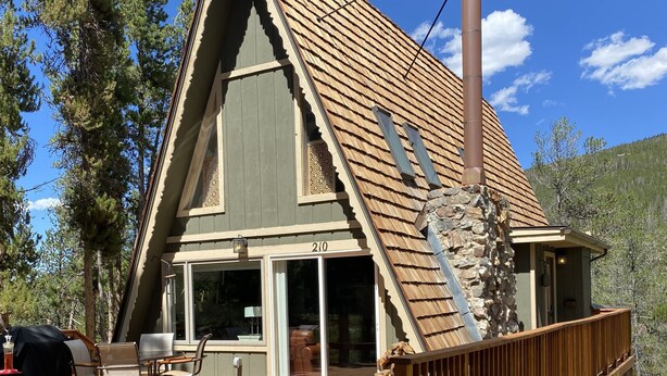 A cabin with a wooden deck, a chimney, and a stone foundation. - Cozy ski chalet 1/2 mile from Main Street, Great Location (Breckenridge)