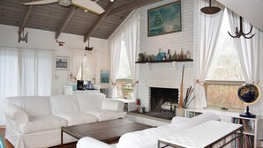 A living room with a white fireplace, white sofas, a coffee table, and a globe on a side table.