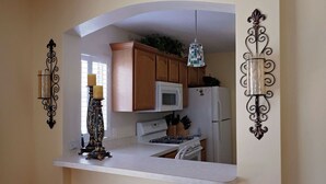 Una cocina con armarios de madera, un microondas blanco y una estufa.