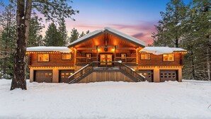 A log cabin with a central staircase, two garages, and a snow-covered landscape.