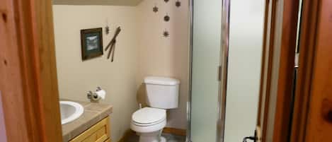 A bathroom with a toilet, sink, and shower.