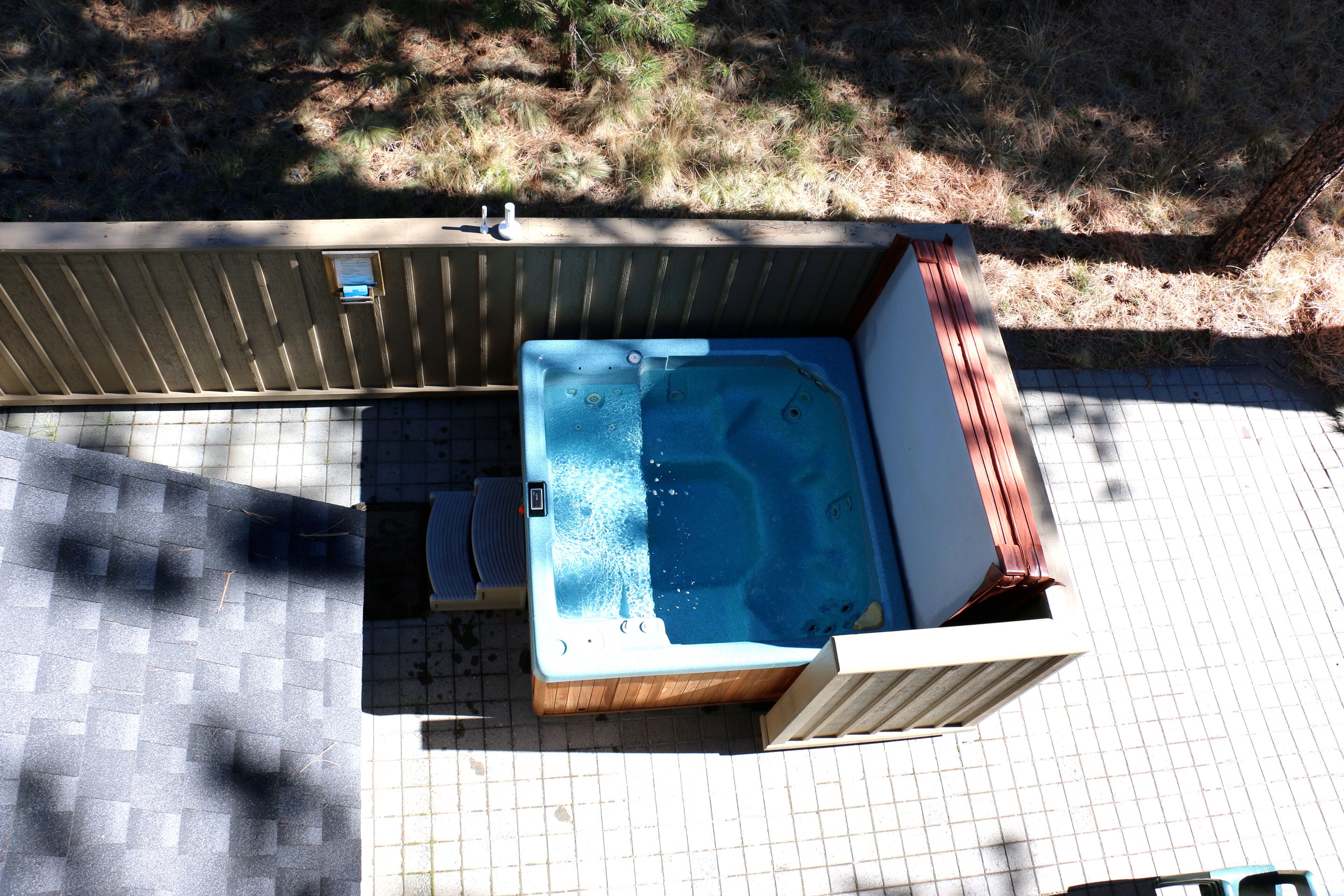 A hot tub in a wooden enclosure with a tiled patio area.