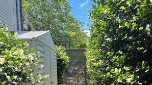 A narrow pathway leading to a gated area with dense foliage on both sides. - Historic Uptown Cottage - 1 mile to Tulane & Loyola (New Orleans)