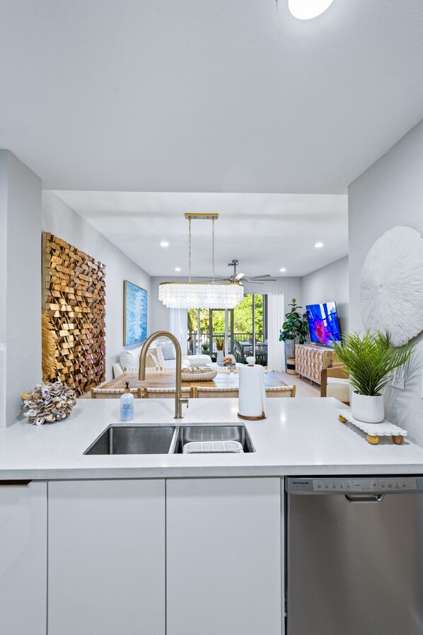 Una cucina moderna con lavastoviglie integrata, un lampadario e un'area pranzo vista esterna.
