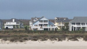 Une propriété située en bord de mer, comprenant plusieurs maisons, dont une grande maison bleue dotée d’un balcon et une plus petite maison blanche.