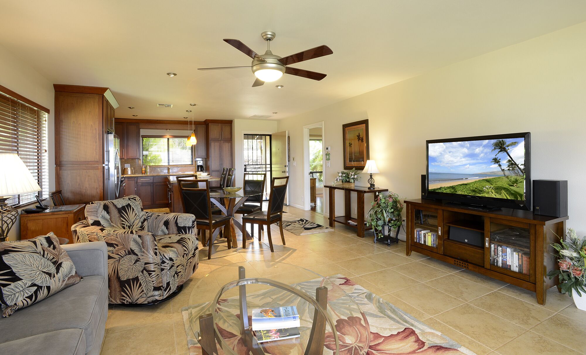 A spacious living room with a ceiling fan, a television, a dining area, and a kitchen.