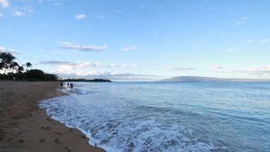 Una spiaggia con impronte sulla sabbia e un mare calmo.